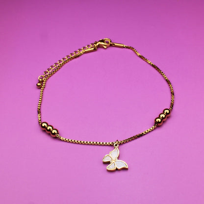 Gold bracelet with a butterfly charm on a pink background