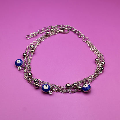 Silver bracelet with blue beads on a pink background