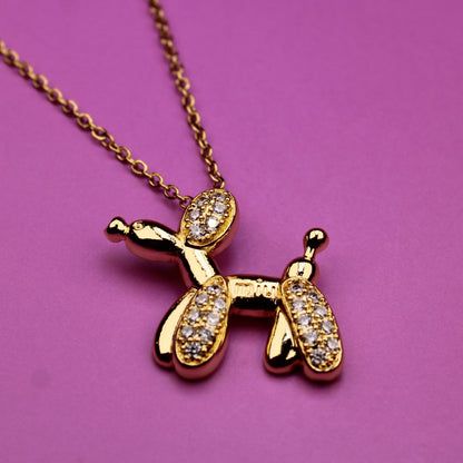 Gold dog-shaped pendant necklace on a pink background