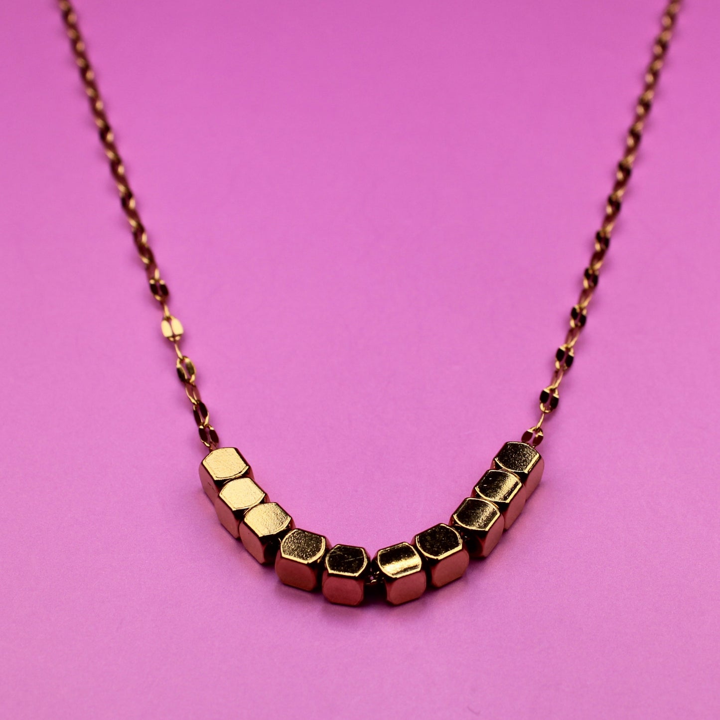 Necklace with geometric beads on a pink background