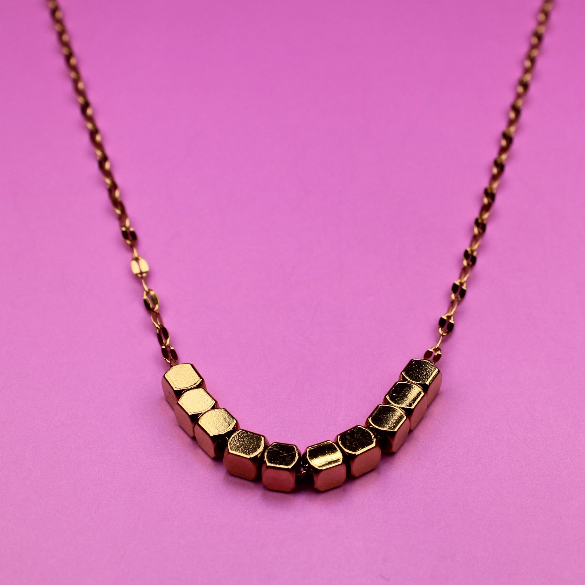 Necklace with geometric beads on a pink background
