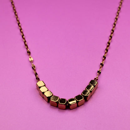 Necklace with geometric beads on a pink background