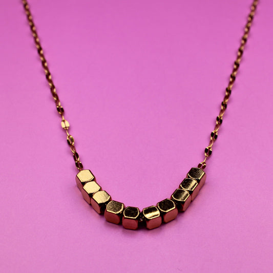 Necklace with geometric beads on a pink background