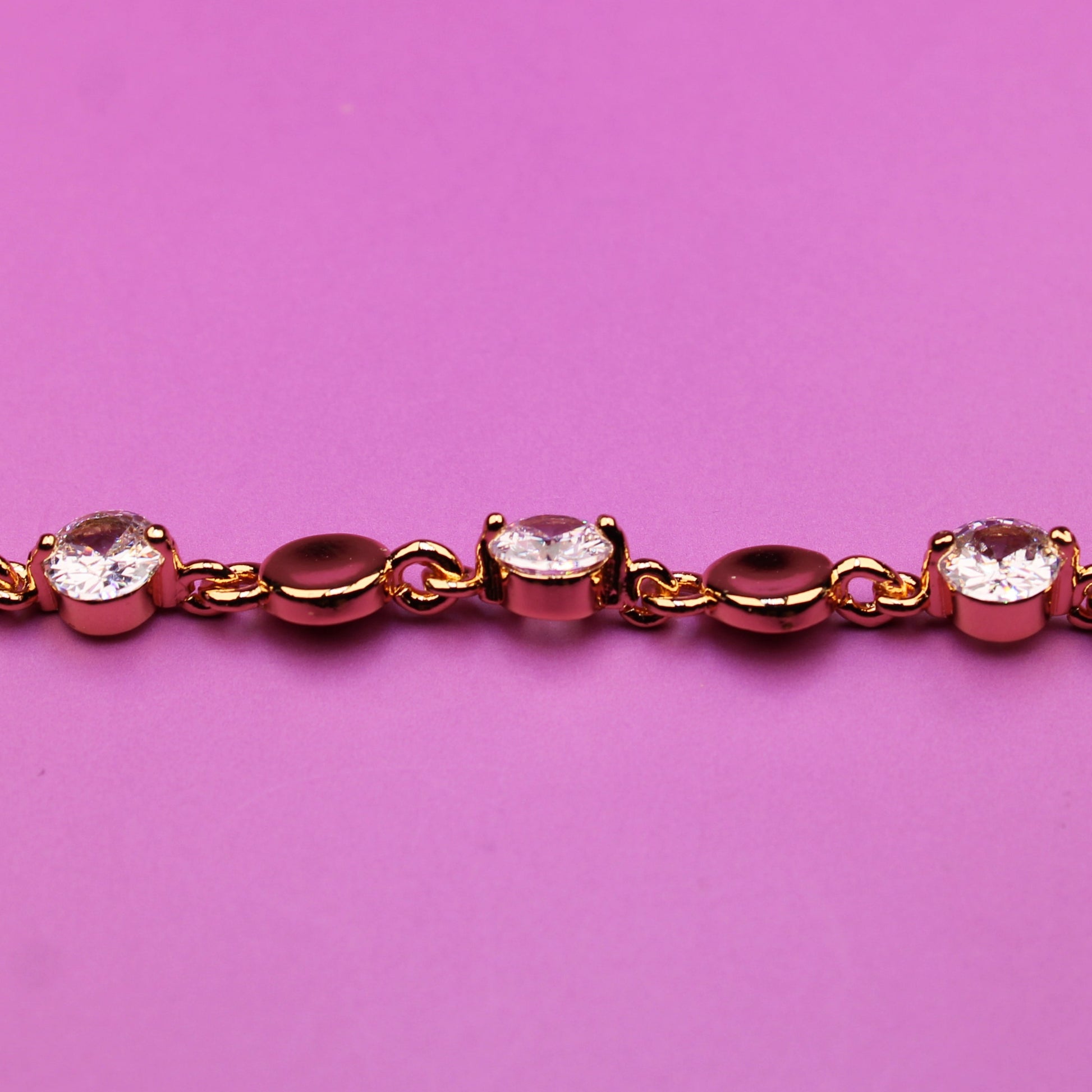 Gold bracelet with small diamonds on a pink background