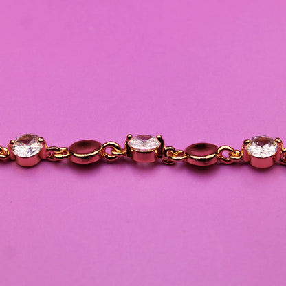 Gold bracelet with small diamonds on a pink background