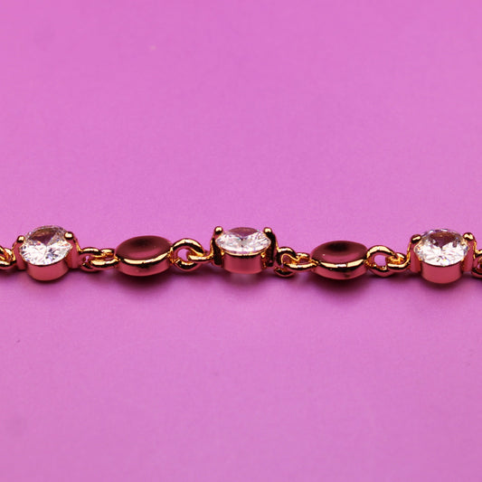 Gold bracelet with small diamonds on a pink background