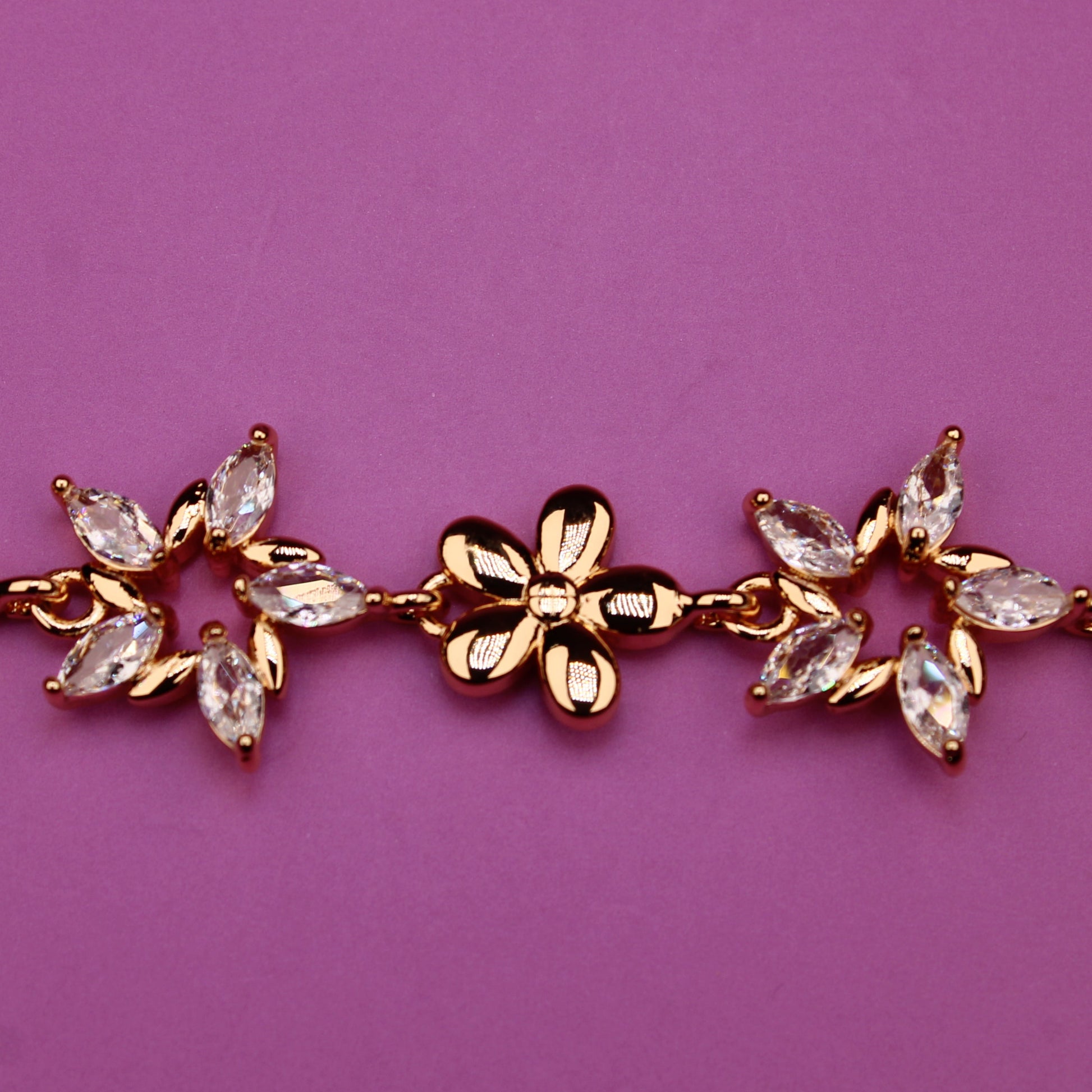 Gold bracelet with floral designs on a purple background
