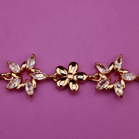 Gold bracelet with floral designs on a purple background