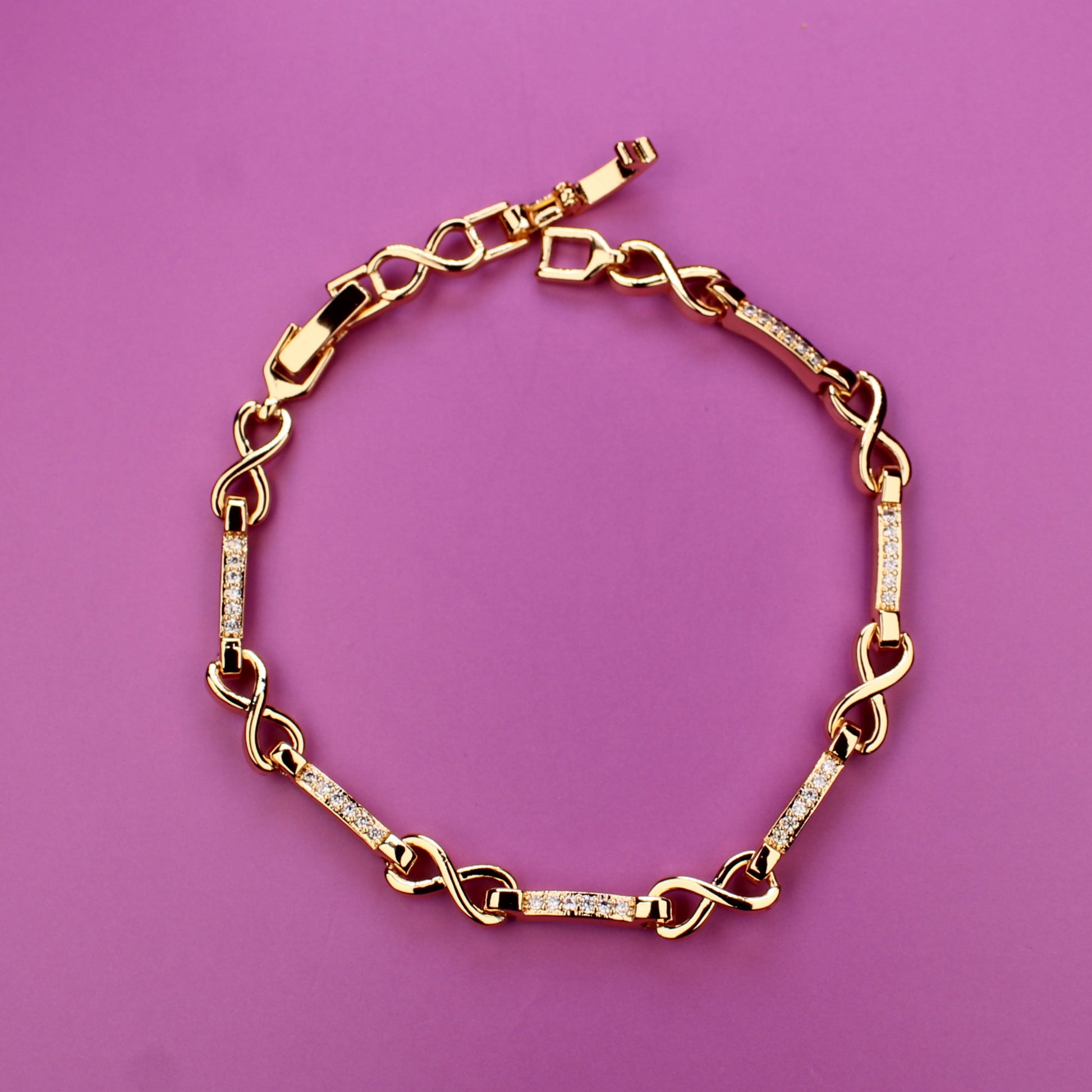 Gold chain bracelet on a pink background
