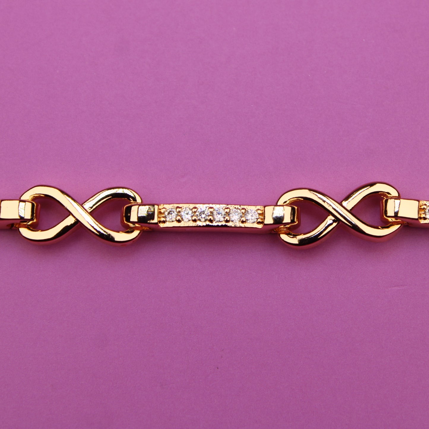 Gold bracelet with diamond accents on a purple background