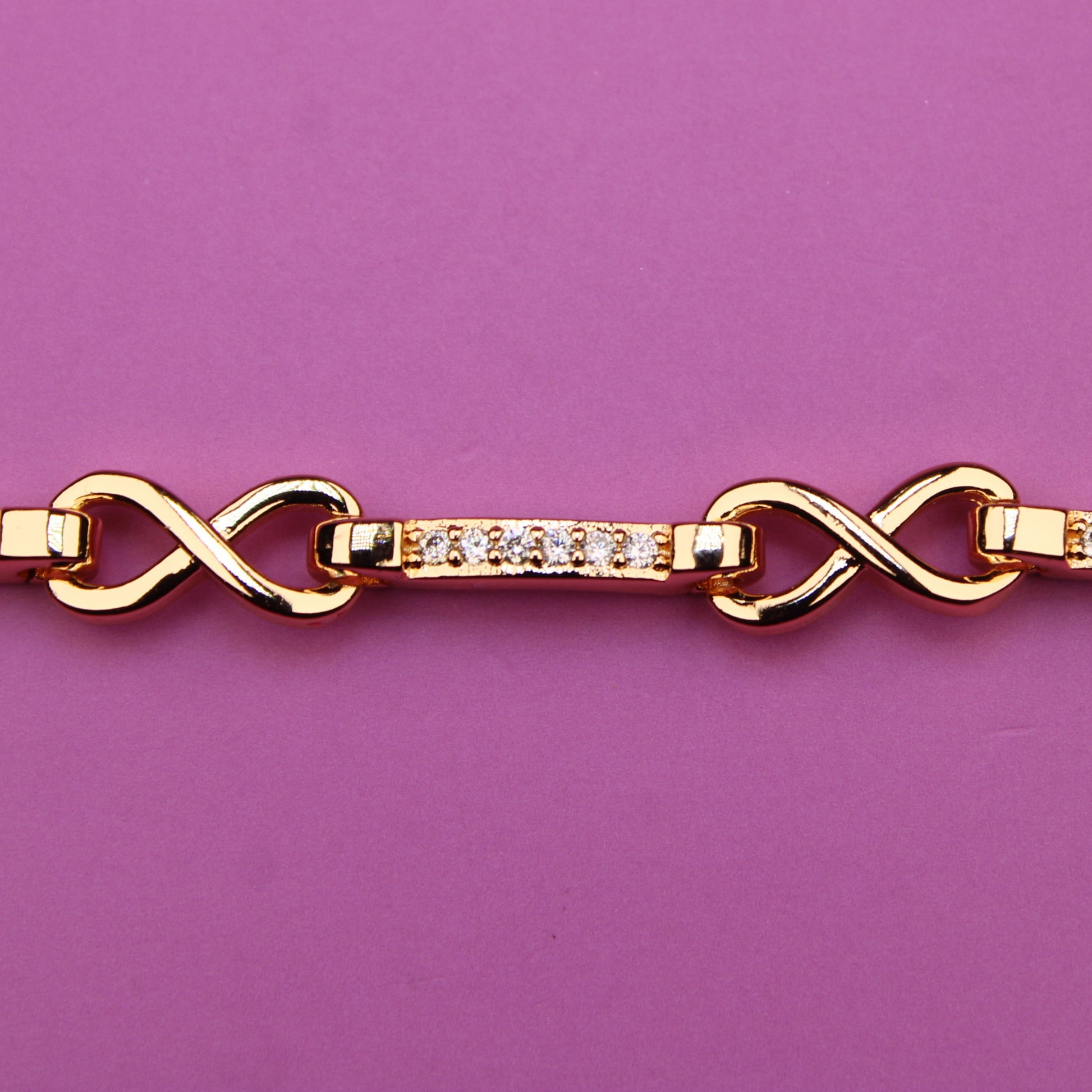 Gold bracelet with diamond accents on a purple background