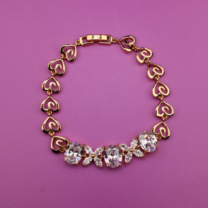 Gold bracelet with heart-shaped links on a purple background