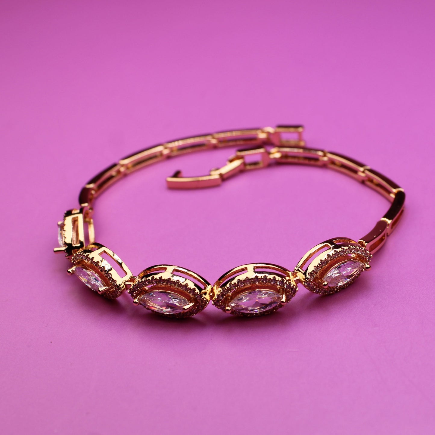 Gold bracelet with pink stones on a pink background