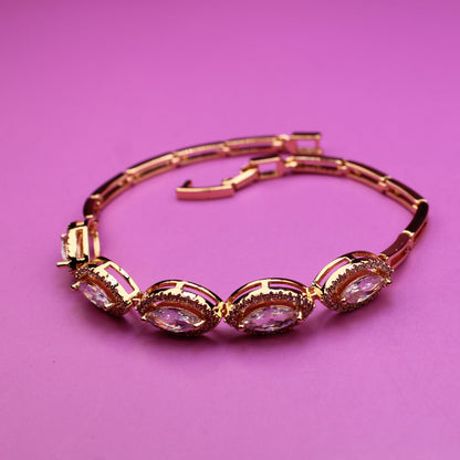 Gold bracelet with pink stones on a pink background