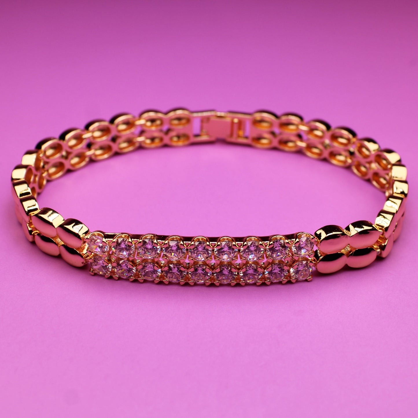 Rose gold bracelet with pink stones on a pink background