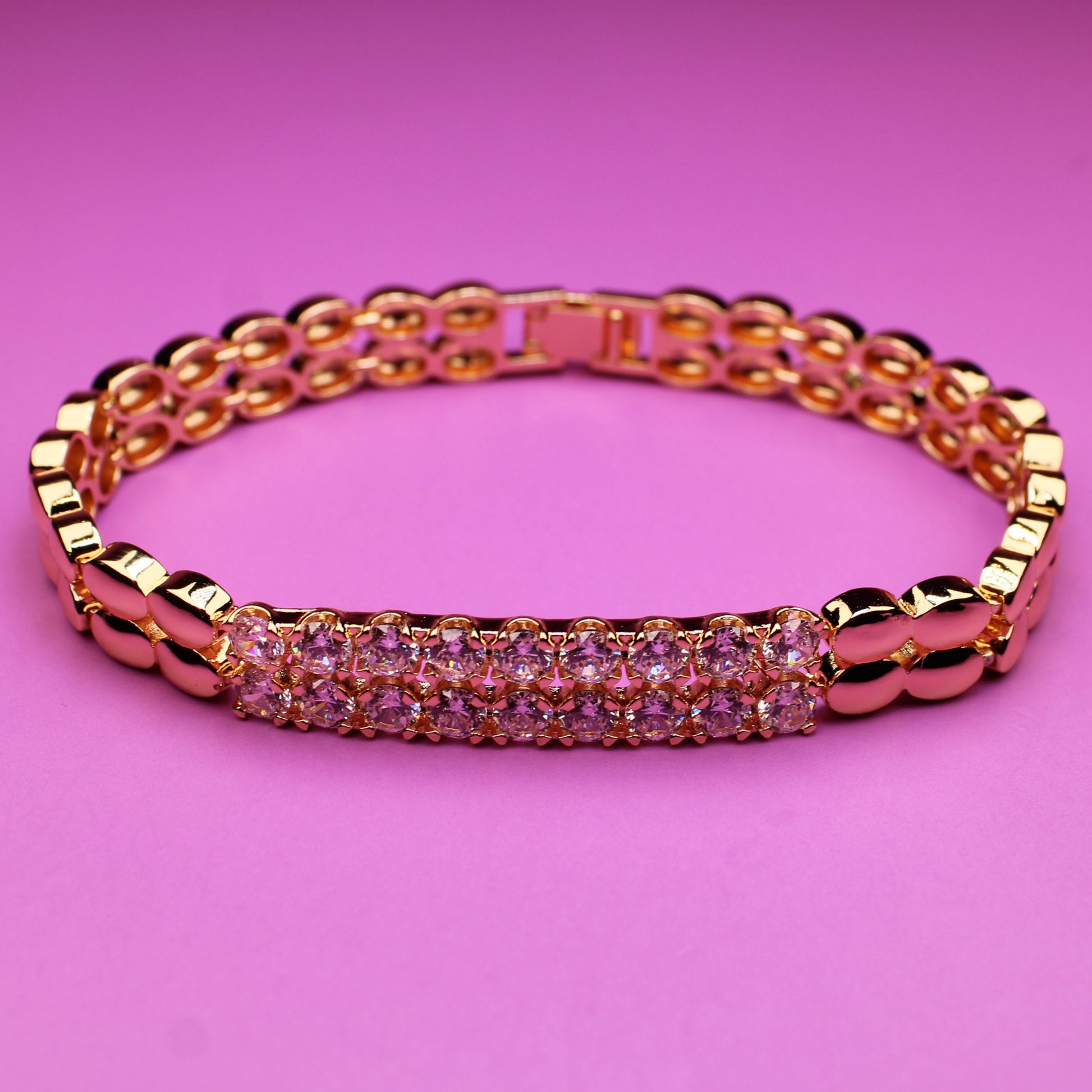 Rose gold bracelet with pink stones on a pink background
