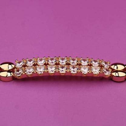 Gold bracelet with a diamond clasp on a pink background