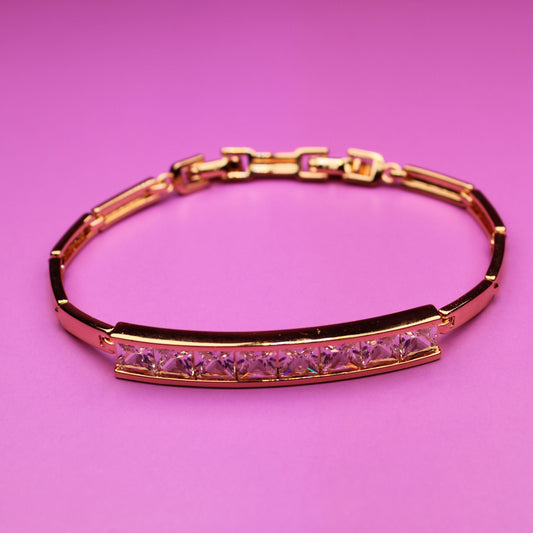 Gold bracelet with pink stones on a pink background