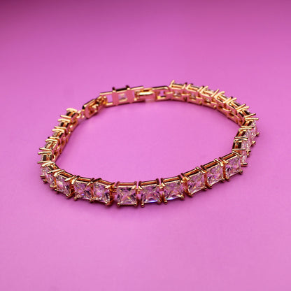 Gold bracelet with pink gemstones on a pink background