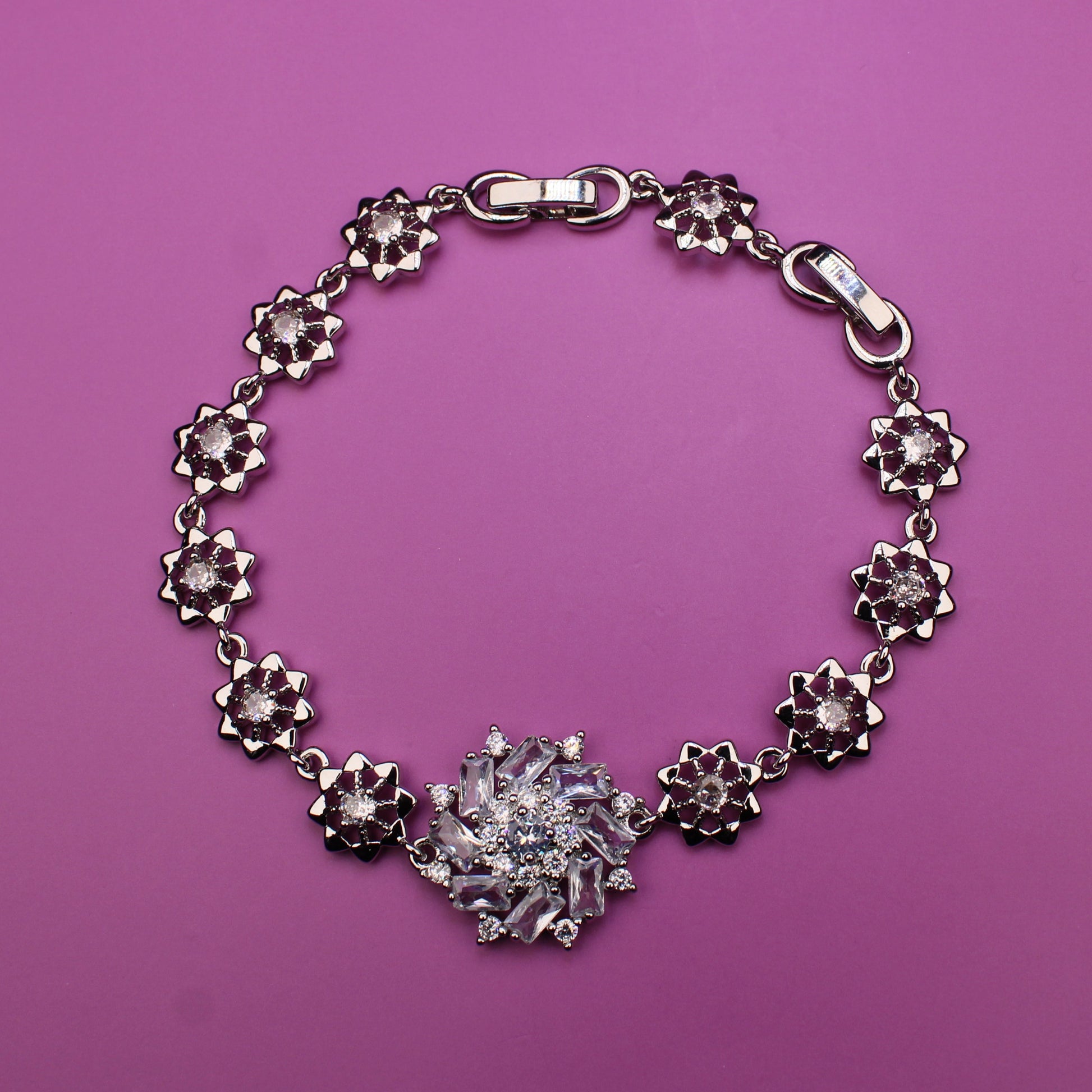 Silver bracelet with floral designs on a pink background