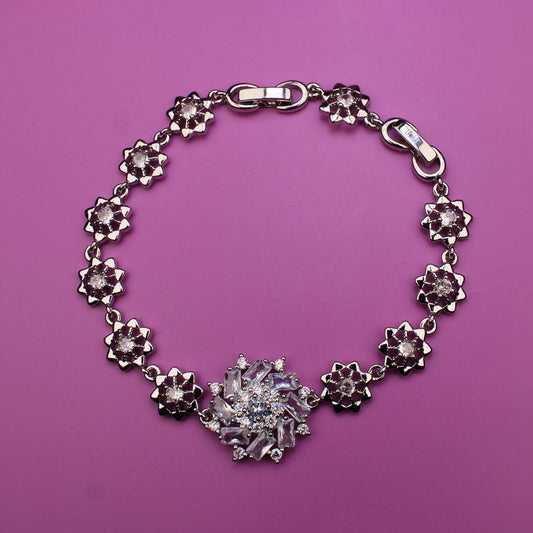 Silver bracelet with floral designs on a pink background