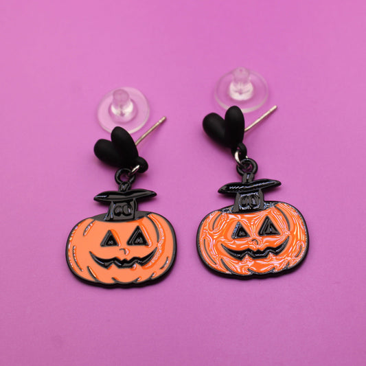 Halloween-themed earrings with jack-o'-lantern design on a pink background