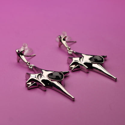 Pair of silver earrings with black stones on a pink background