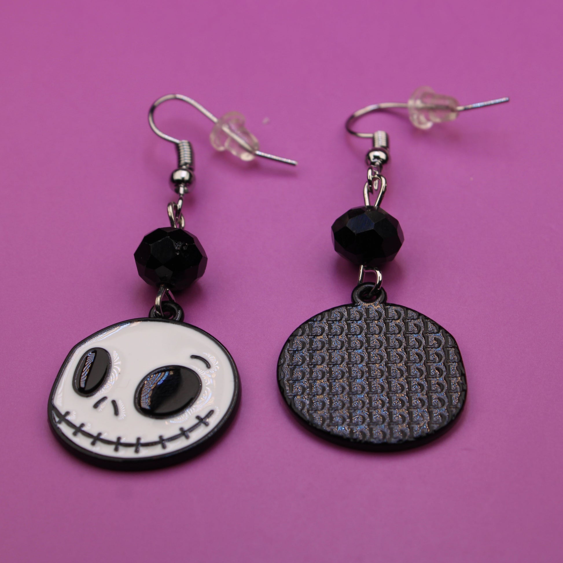 Pair of earrings with black and white designs on a pink background
