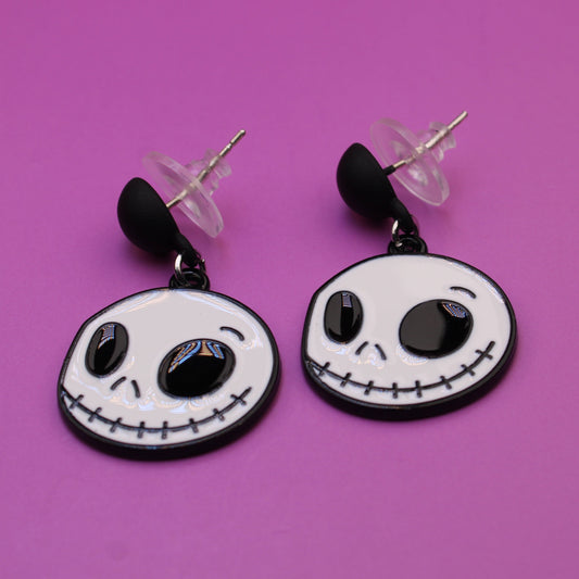Skull-shaped earrings on a pink background