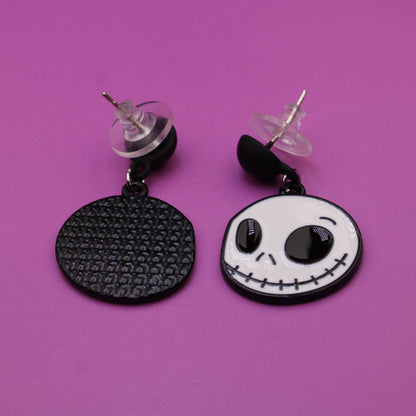 Pair of earrings with skull design on a purple background