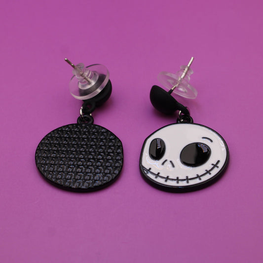 Pair of earrings with skull design on a purple background