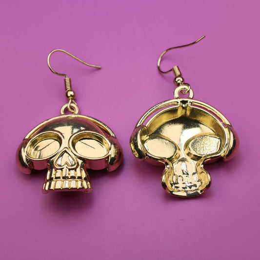 Gold skull-shaped earrings on a purple background