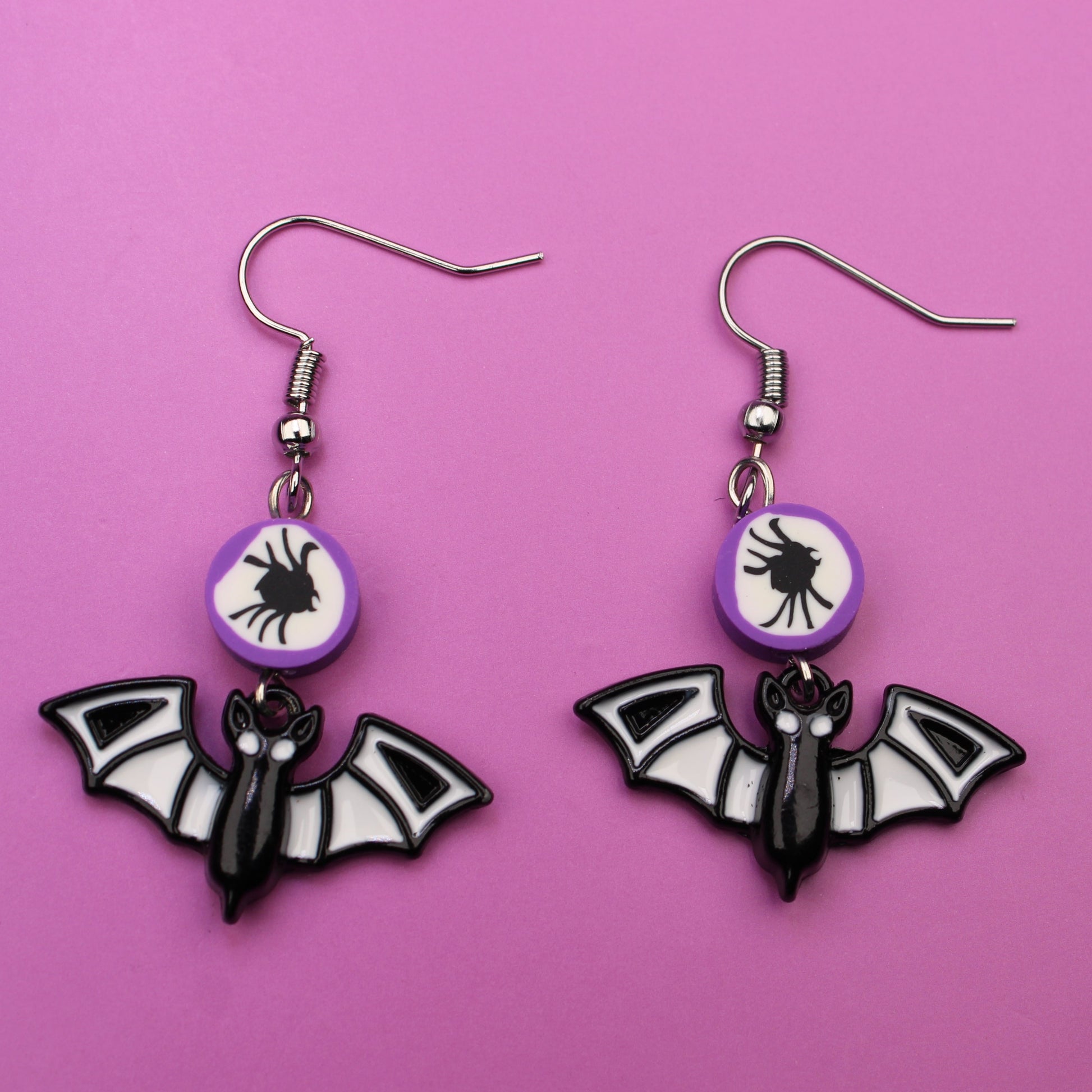 Bat-shaped earrings on a pink background