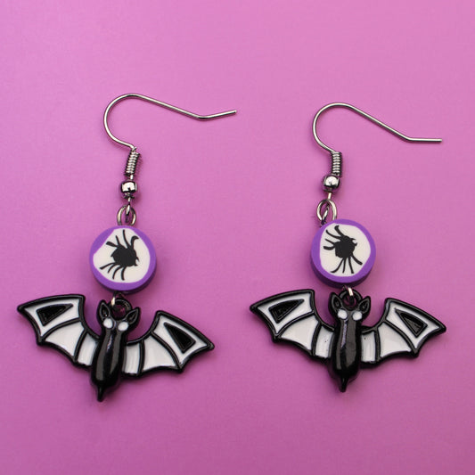Bat-shaped earrings on a pink background