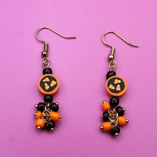 Pair of Halloween-themed beaded earrings on a pink background