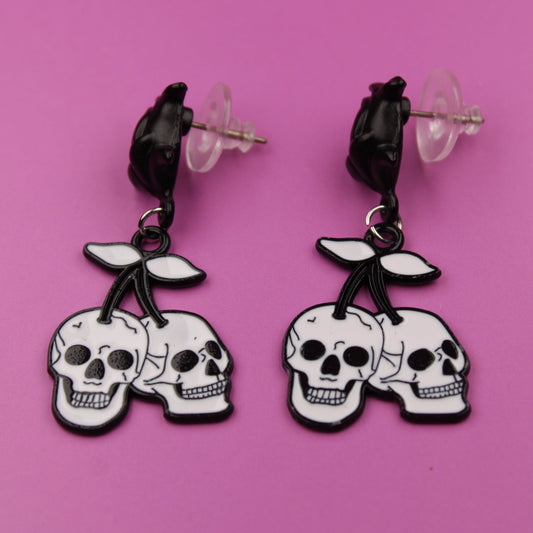 Skull-shaped earrings on a pink background