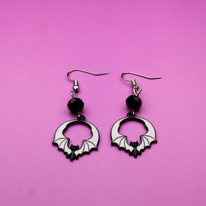 Pair of hoop earrings with black beads on a pink background
