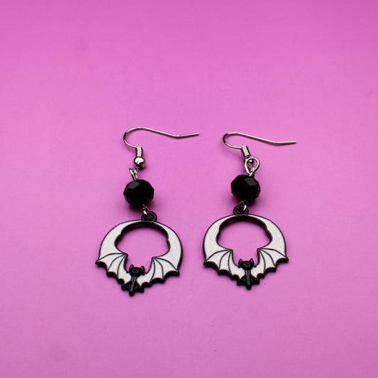 Pair of hoop earrings with black beads on a pink background