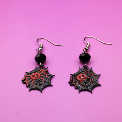 Pair of spider web earrings on a pink background