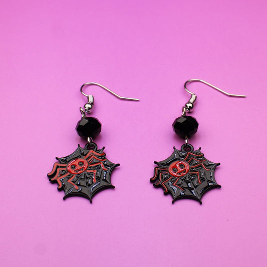 Pair of spider web earrings on a pink background
