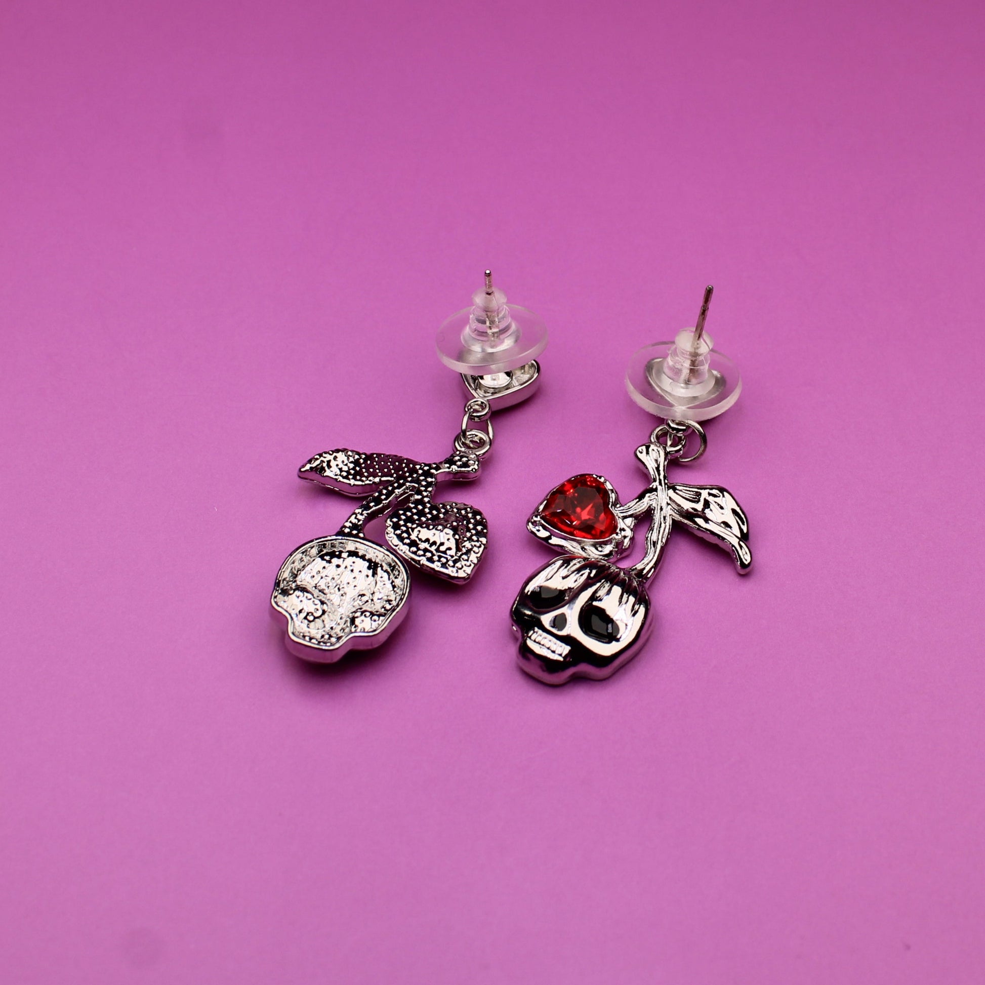 Pair of earrings with decorative charms on a pink background