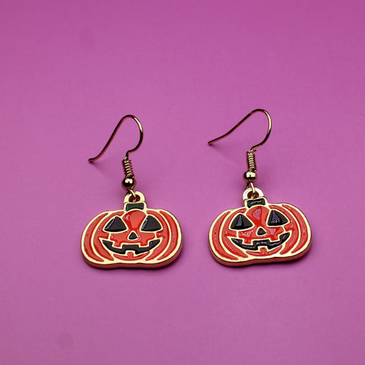 Pumpkin-shaped earrings on a purple background