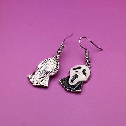 Pair of skeleton hand earrings on a pink background