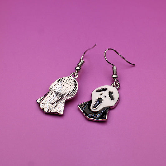 Pair of skeleton hand earrings on a pink background
