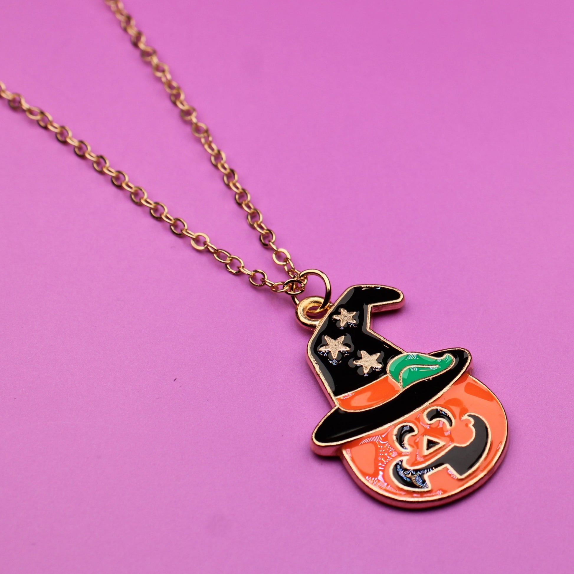 Pumpkin-shaped pendant with a witch on a pink background