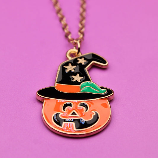 Halloween-themed necklace with a pumpkin and witch hat pendant on a pink background