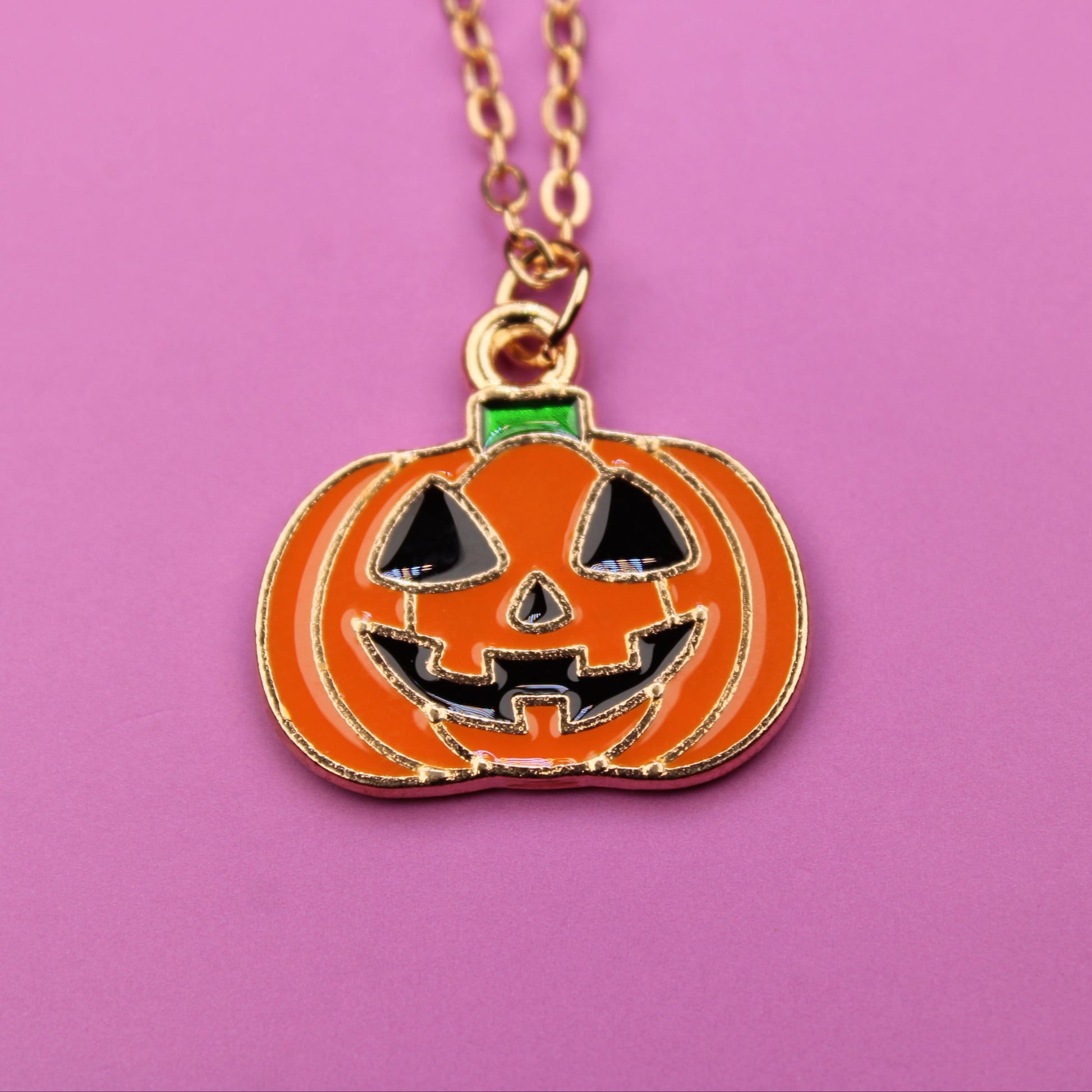 Pumpkin-shaped pendant necklace on a pink background