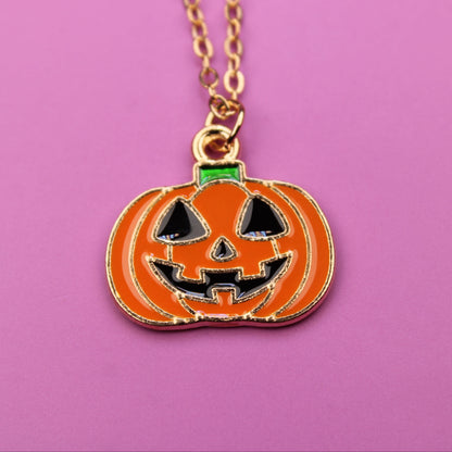 Pumpkin-shaped pendant necklace on a pink background