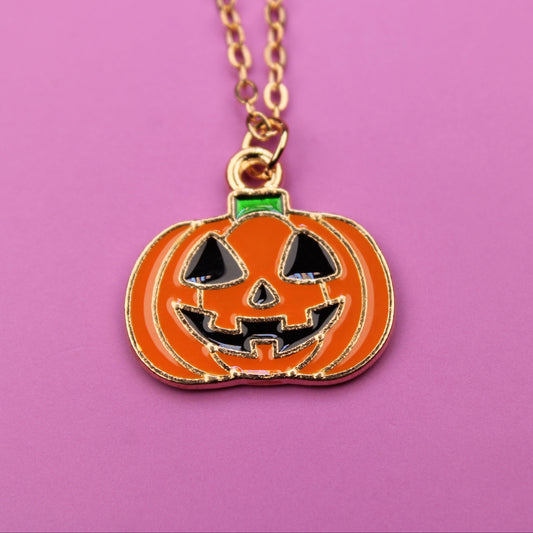 Pumpkin-shaped pendant necklace on a pink background