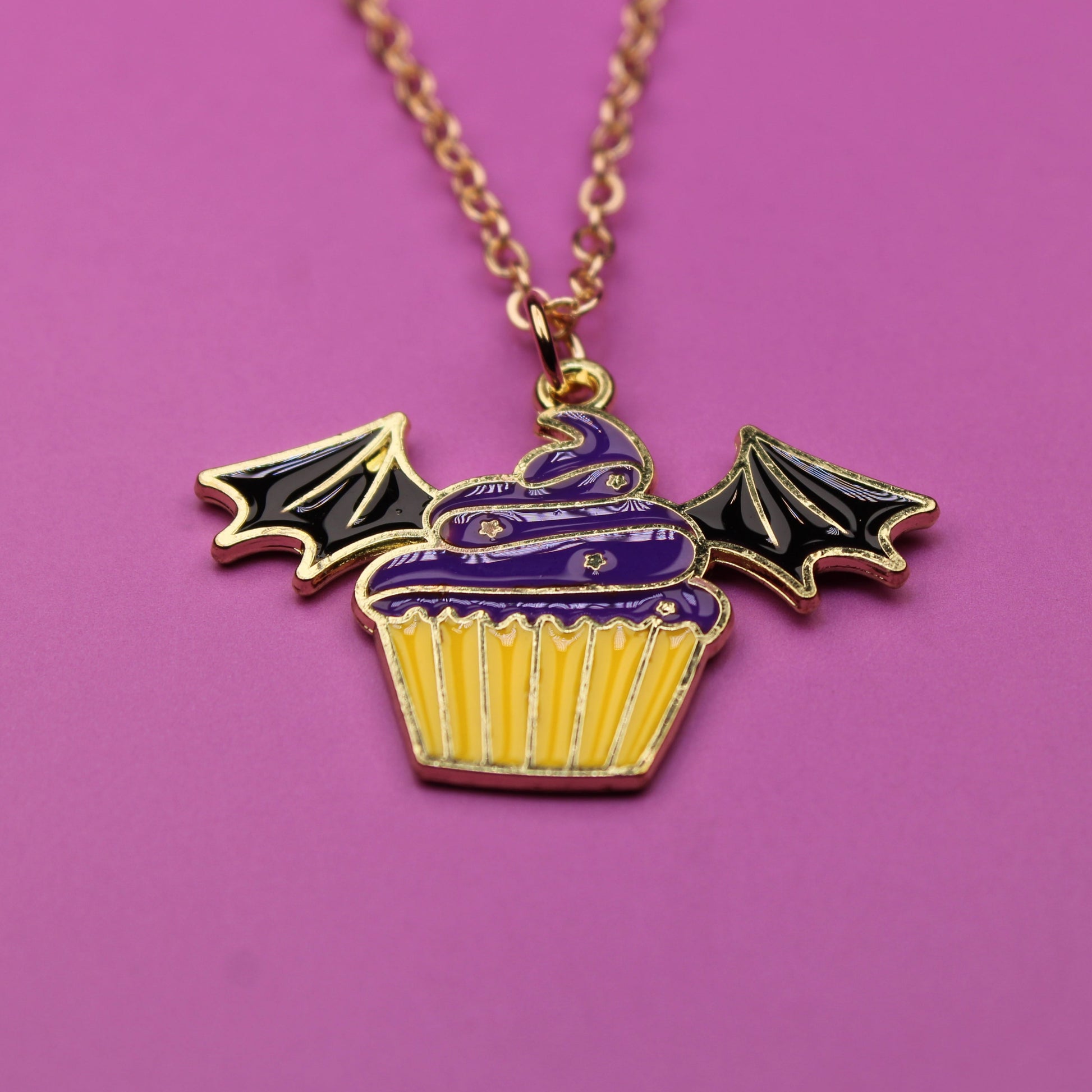 Necklace with a cupcake pendant featuring bat wings on a purple background
